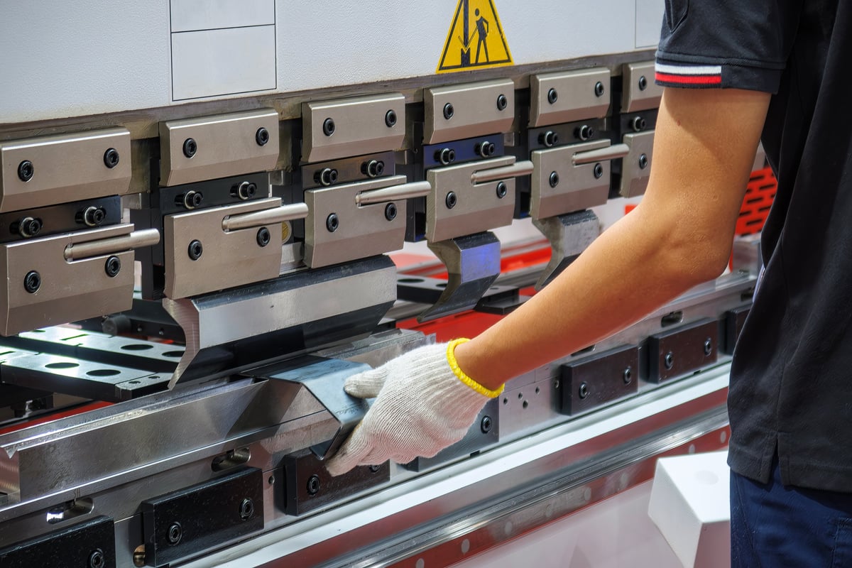 Close up the press brake bending machine operator hold the sheet metal parts with safety glove. The sheet metal working operation by skill operator.