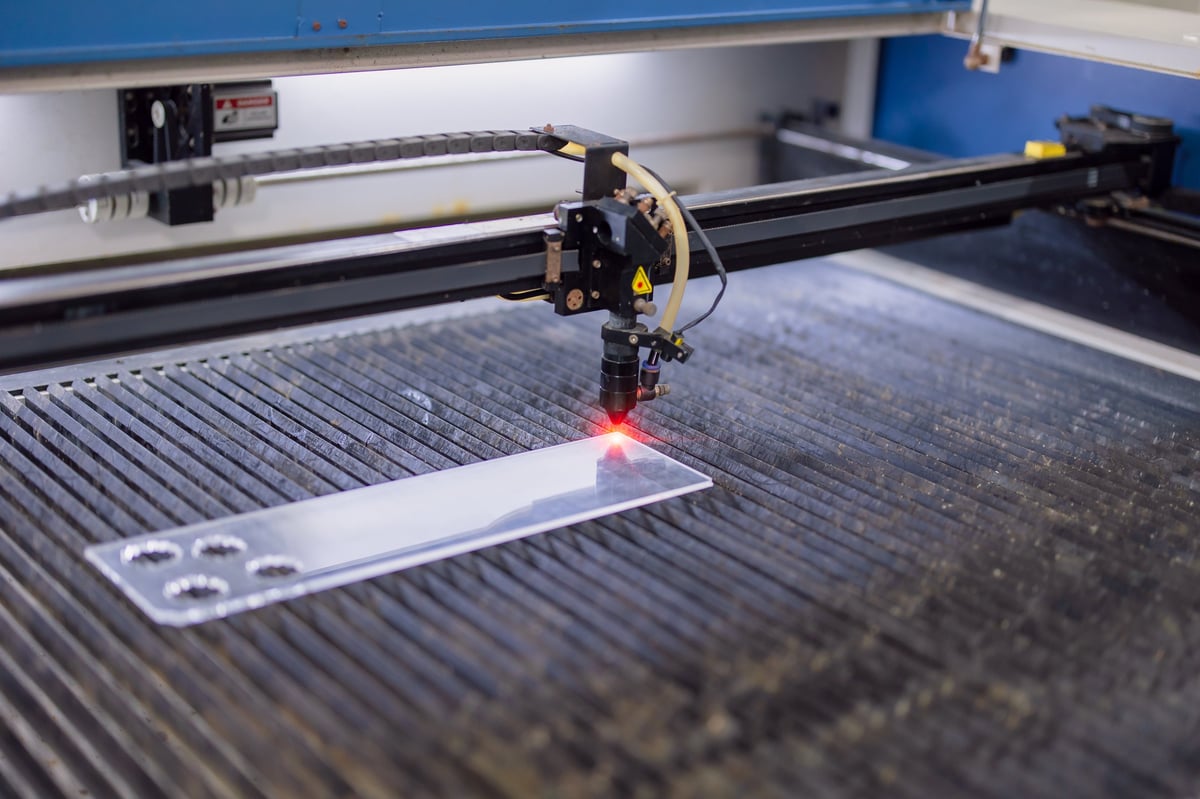Closeup industrial CO2 laser cutting machine working with high powered red laser beam on metal plate